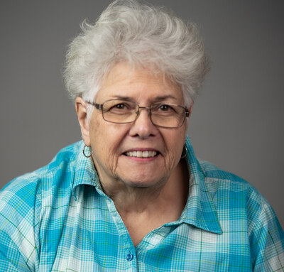 Chris Wistrom, a woman with short gray hair and glasses, smiling in a turquoise plaid shirt.