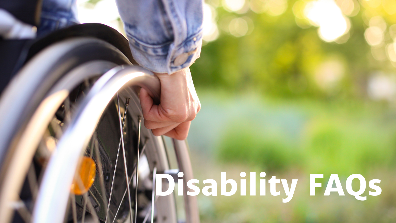 A hand grips the push rim of a wheelchair. 