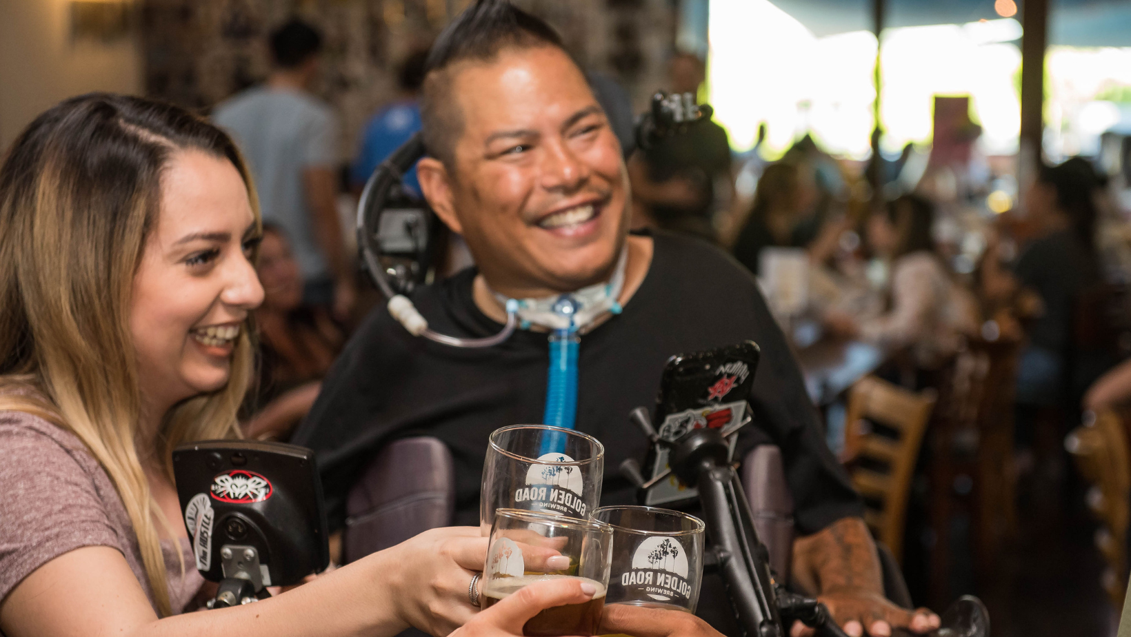 A man using a ventilator enjoys a brewery with his wife. 
